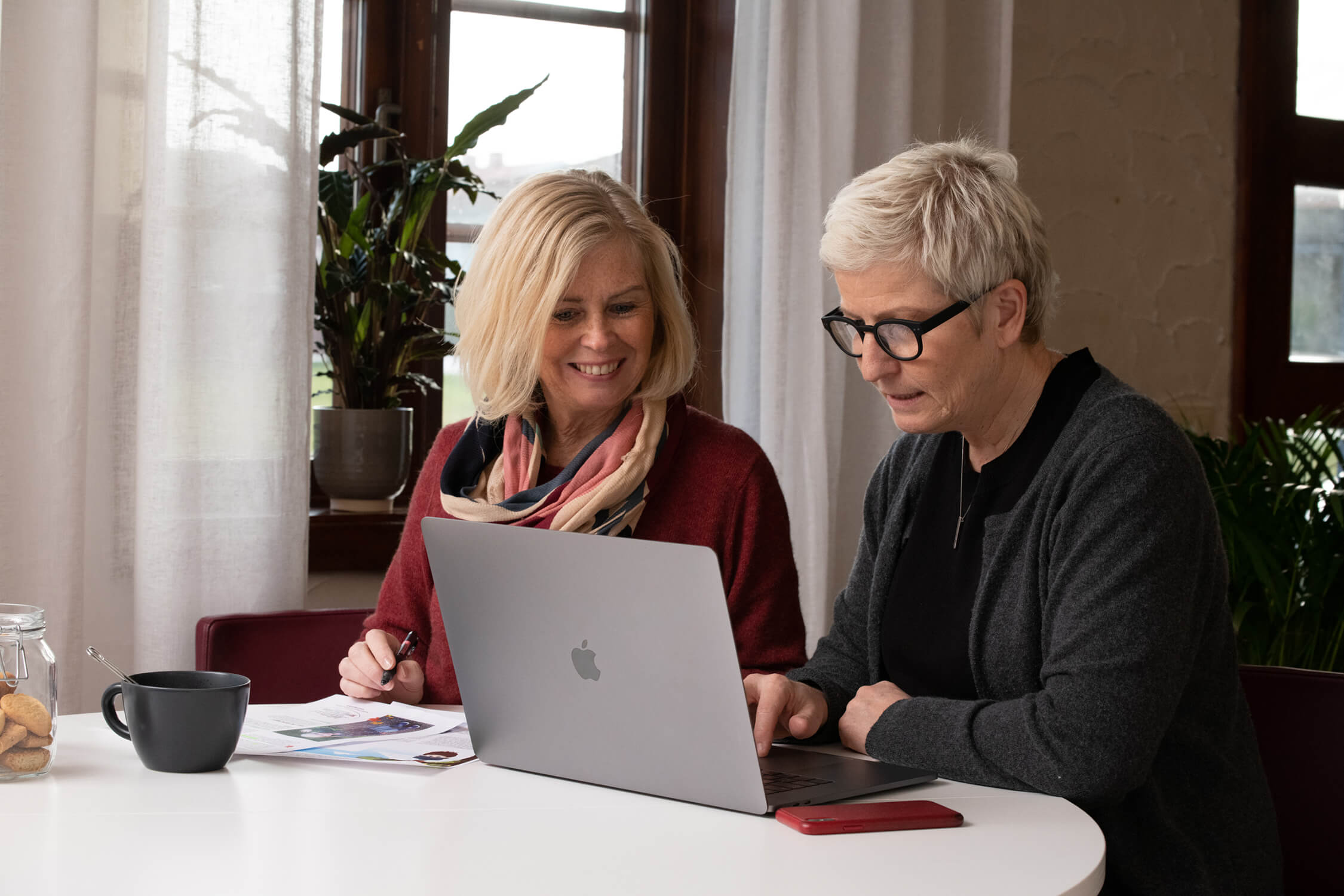 Två kvinnor som sitter bedvid varandra och kollar på en dator